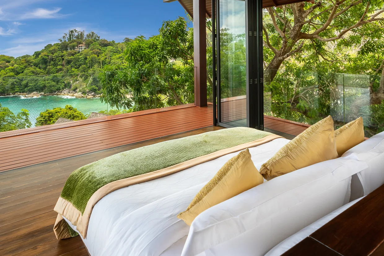 A bedroom with bifold glass doors opening to the sea