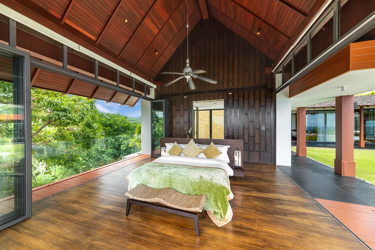 A bedroom set under a pitched teak ceiling with a timber floor