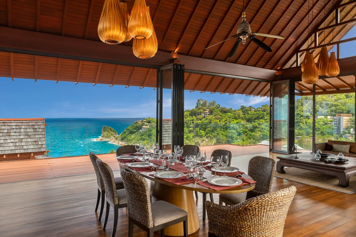The dining pavilion under its teak ceiling and amber pendant lights, open to the ocean
