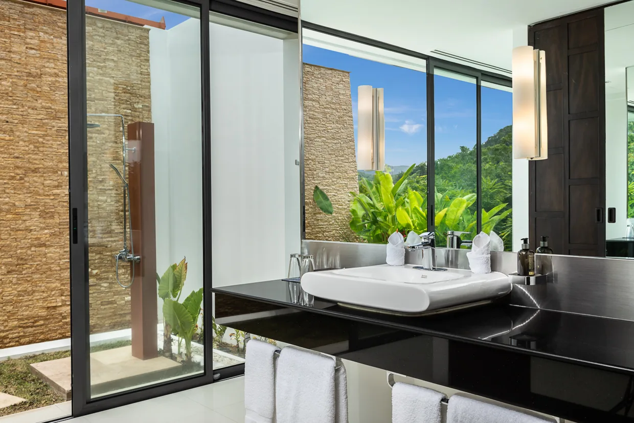 An ensuite bathroom with a stone wall and its own outdoor shower garden