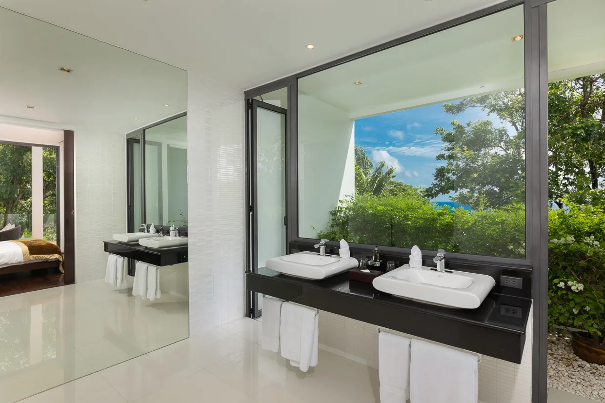 An ensuite bathroom with twin basins and a garden outlook