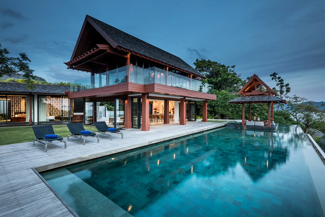 The infinity pool at dusk with the villa lit behind it