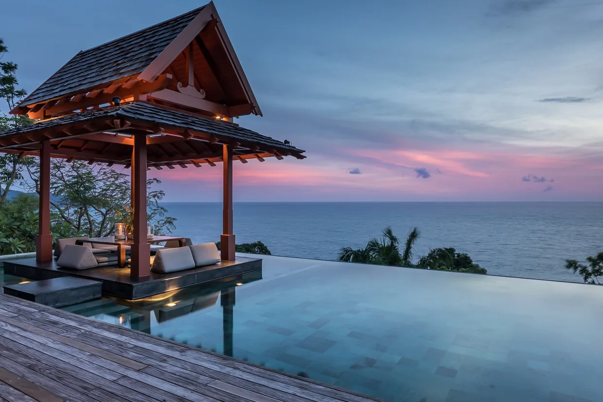 The sala at the pool's edge under a pink dusk sky